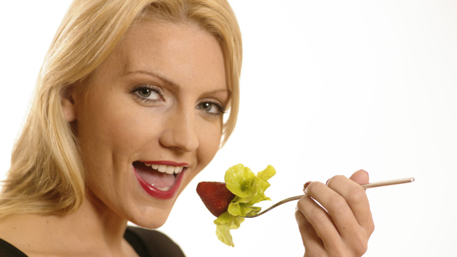 Frau mit Erdbeere für ein Fitnessfoto